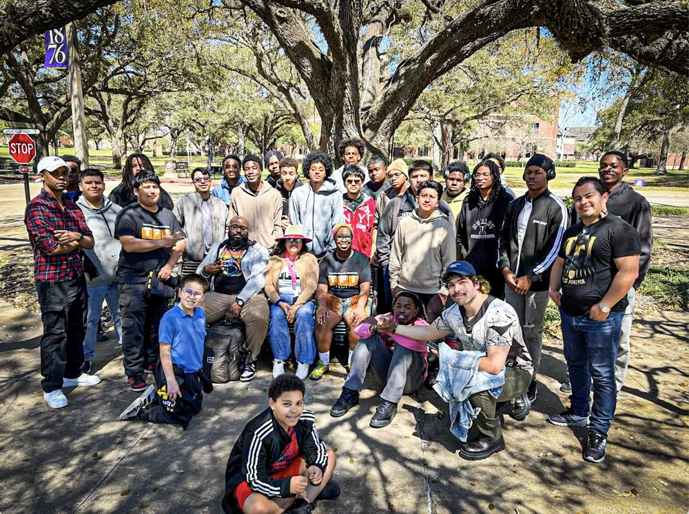 A large group of students outdoors under oak trees